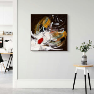 The canvas artwork "Never Stop" is displayed in a dark brown floating frame on a hallway wall. A small stool with a vase and plants sits to the right of the artwork, adding a natural touch. In the background on the left, part of an office desk is visible, subtly connecting the artwork’s theme of persistence to a productive and motivational environment.