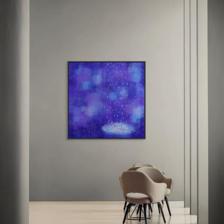 A big canvas print in a floating frame is on the gray wall in the public space in front of a few chairs.